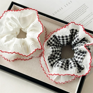 Red plaid and white lace scrunchies set with elastic hair bands in a decorative tray