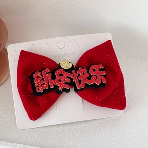 Detail of red velvet bow hair clip with gold heart and New Year greeting on card