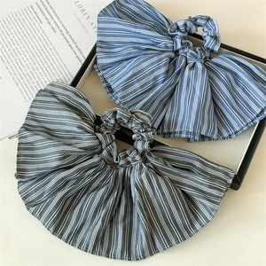 Close-up of elegant striped oversized bow scrunchies on a minimalist display tray