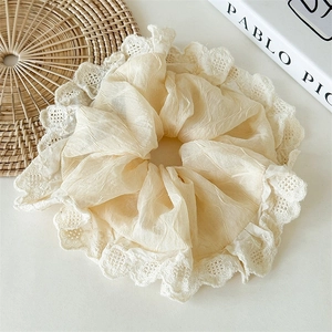 Elegant beige lace pleated scrunchie for women shown with artistic book and woven mat decor