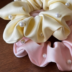 Gros plan de chouchous en satin rose et jaune avec des perles élégantes