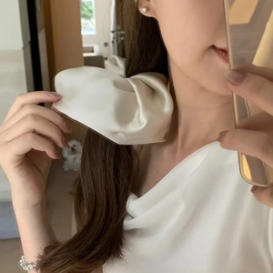 Dettaglio di un elegante elastico per capelli a fiocco in raso bianco sporco con seta