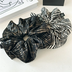 Detail of oversized striped scrunchies with satin sheen and floral logo labels