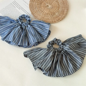 Close-up of pleated striped fabric scrunchie in navy blue and dark grey with soft textures