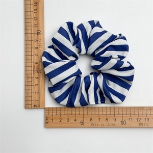 Draufsicht auf blau gestreiftes Scrunchie auf weißem Grund mit Holzlinealen zur Maßangabe