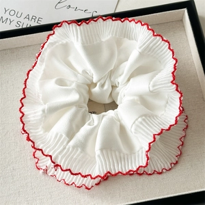 Detail of white scrunchie with red scalloped edges and textured ribbed fabric
