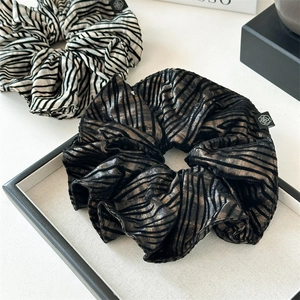 Detail of zebra stripe scrunchies with metallic texture and rose woven label