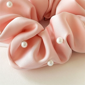 Gros plan détaillé du chouchou en satin rose avec perles blanches et texture soyeuse