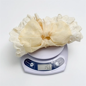Macro detail of a lace scrunchie weighing 15.6g on a scale to show product weight