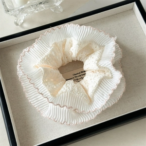 Détail du chouchou en dentelle double couche avec bords ondulés roses et tissu beige