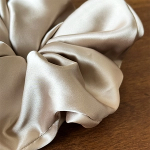 Dettaglio dell'elastico in raso oro champagne che mostra la trama setosa e le pieghe
