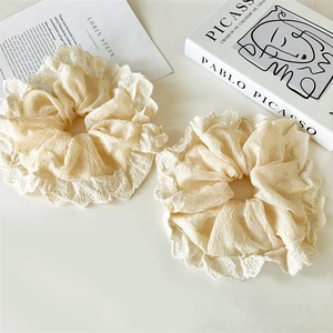 Close-up of two beige lace scrunchies on a minimalist background with artistic books