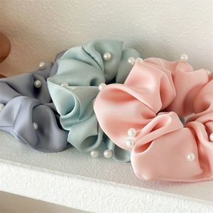 Vue détaillée de trois chouchous en satin avec perles en gris-bleu, vert clair et rose doux