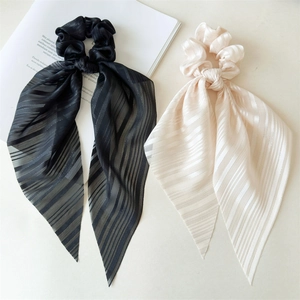 Détail de chouchous élégants noirs et crème avec de longs rubans sur un fond clair et doux