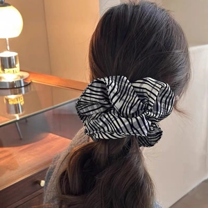 Macro shot of oversized zebra striped scrunchie on a stylish ponytail in a cozy setting