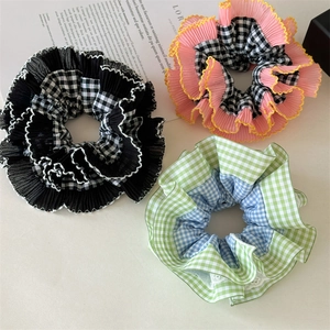 Trois grands chouchous à carreaux aux motifs colorés posés sur un fond beige neutre