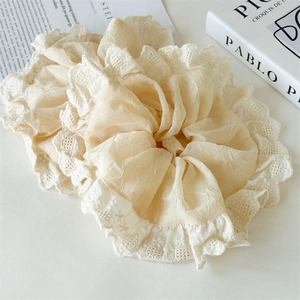 Detailed macro view of beige chiffon scrunchie with delicate white lace embroidery trim