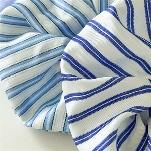 Nahaufnahme des blau-weiß gestreiften Seidentextur-Scrunchie mit feiner diagonalen Webstruktur