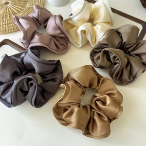Detail of five assorted satin scrunchies in elegant Morandi colors with silk texture