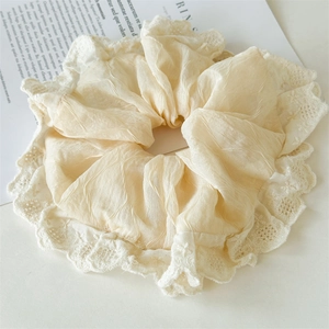 Close-up of a cream lace oversized scrunchie with soft ruffled fabric and delicate details