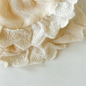 Close-up of cream lace scrunchie showing detailed pleated fabric and floral embroidery