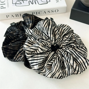 Elegant zebra stripe scrunchies in black and gold velvet texture on a Picasso book