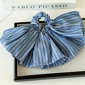 Detailed view of a blue and white striped fabric scrunchie with large ruffled bow design