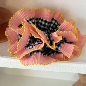 Détail d'un chouchou plissé rose avec bordure jaune et superposition à motif vichy