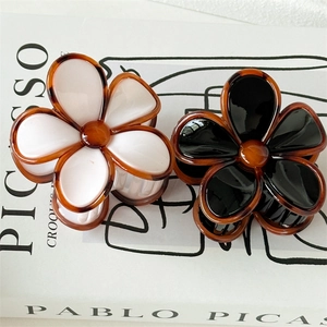 Détail de pinces à cheveux fleur noire et blanche avec texture ambre écaille de tortue