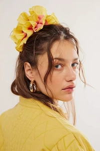 Vue détaillée d'un chouchou à fleurs jaune et de créoles dorées sur un mannequin