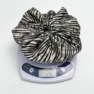 Detail shot of striped scrunchie on electronic scale showing lightweight 26.7g mass
