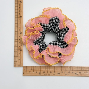 Détail d'un chouchou géant rose à carreaux montrant une taille de 15 cm avec une règle graduée