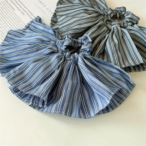 Close-up of pleated striped scrunchies in blue and grey with elegant ruffled fabric details