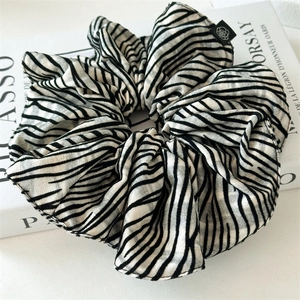 Close-up of zebra stripe scrunchie with detailed fabric texture on a minimalist book
