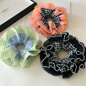 Détail de chouchous à carreaux roses, bleus et noirs avec texture froissée et bords ondulés
