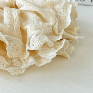 Close-up of cream scrunchie with intricate lace embroidery and vintage fabric texture