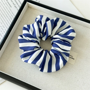 Detail eines blau-weiß gestreiften Stoff-Haargummis in einer eleganten Geschenkbox