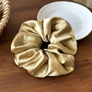 Dettaglio macro dell'elastico in raso oro champagne con eleganti pieghe e trama lucida