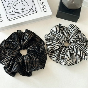Detailed view of zebra pattern silk scrunchies with floral logo labels on art books
