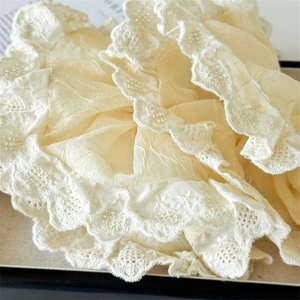 Elegant cream lace scrunchie with intricate embroidery details for a sweet ponytail style