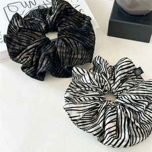 Close-up of animal print satin scrunchies in black and white with rose logo detail