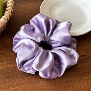 Dettaglio macro dell'elastico in raso viola chiaro liscio su una base di legno