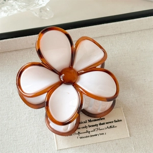 Détail d'une pince à cheveux fleur blanc perle avec bords en écaille de tortue ambre