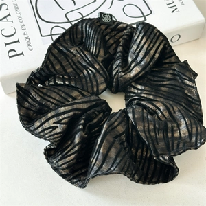 Detail shot of large black scrunchie with gold metallic zebra stripes on white book