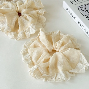 Detailed macro view of two cream lace scrunchies with elegant ruffled fabric textures