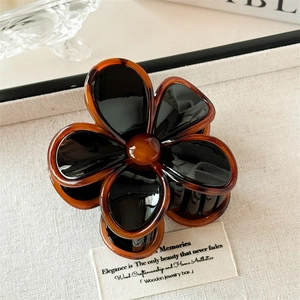 Détail de la pince à cheveux fleur ambrée avec pétales noirs brillants en résine