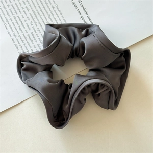 Macro shot of charcoal grey satin scrunchie showing fabric texture and pleated edge