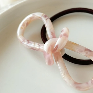 Détail d'un nœud en acétate marbré rose sur un élastique à cheveux haute élasticité