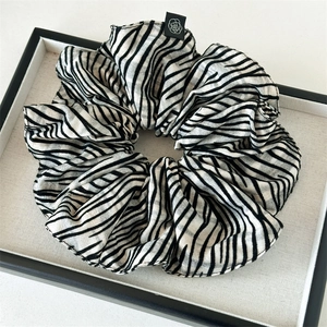Detail of black and white striped hair scrunchie with floral tag on a display tray