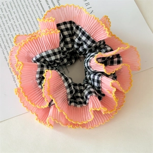 Détail d'un chouchou rose en mousseline plissée avec motif à carreaux et bords jaunes